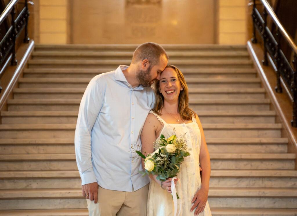 Bruidspaar samen op een brede stenen trap, ontspannen en liefdevol vastgelegd tijdens hun bruiloft.