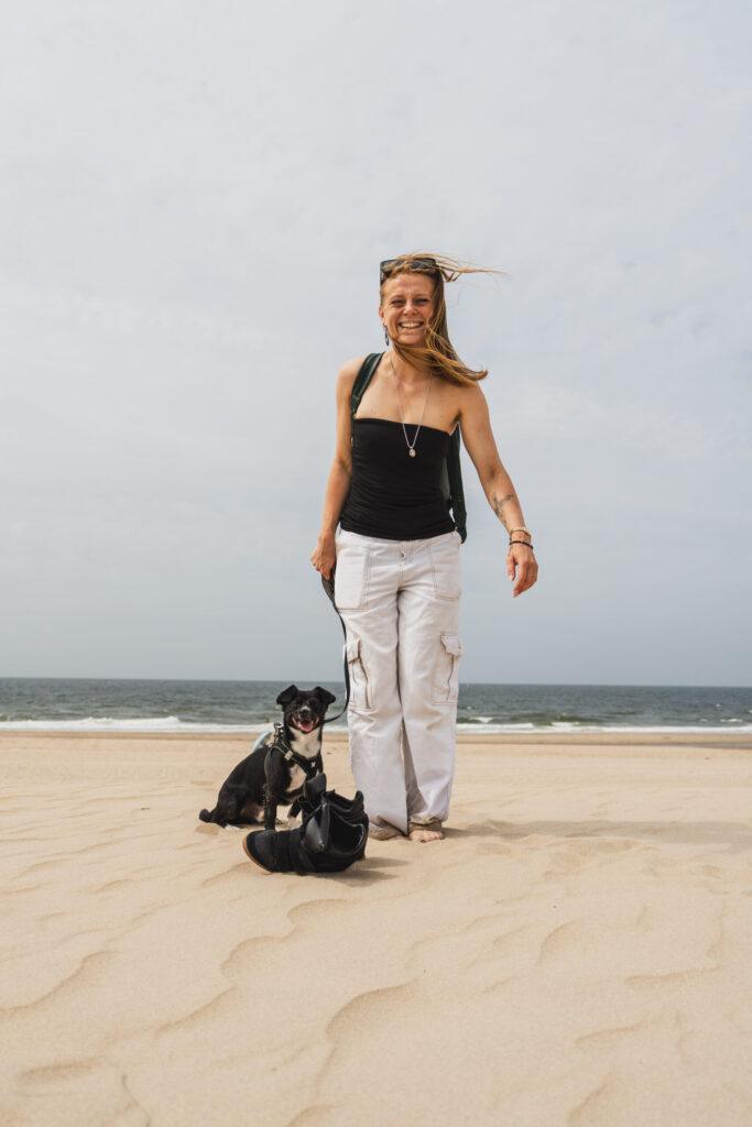 Vrouw loopt met haar hond over het strand van Scheveningen in Den Haag, met de zee op de achtergrond.
