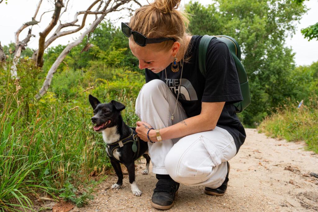 Vrouw zit gehurkt bij haar hond op een pad nabij Scheveningen in Den Haag, vastgelegd in spontane lifestyle fotografie.