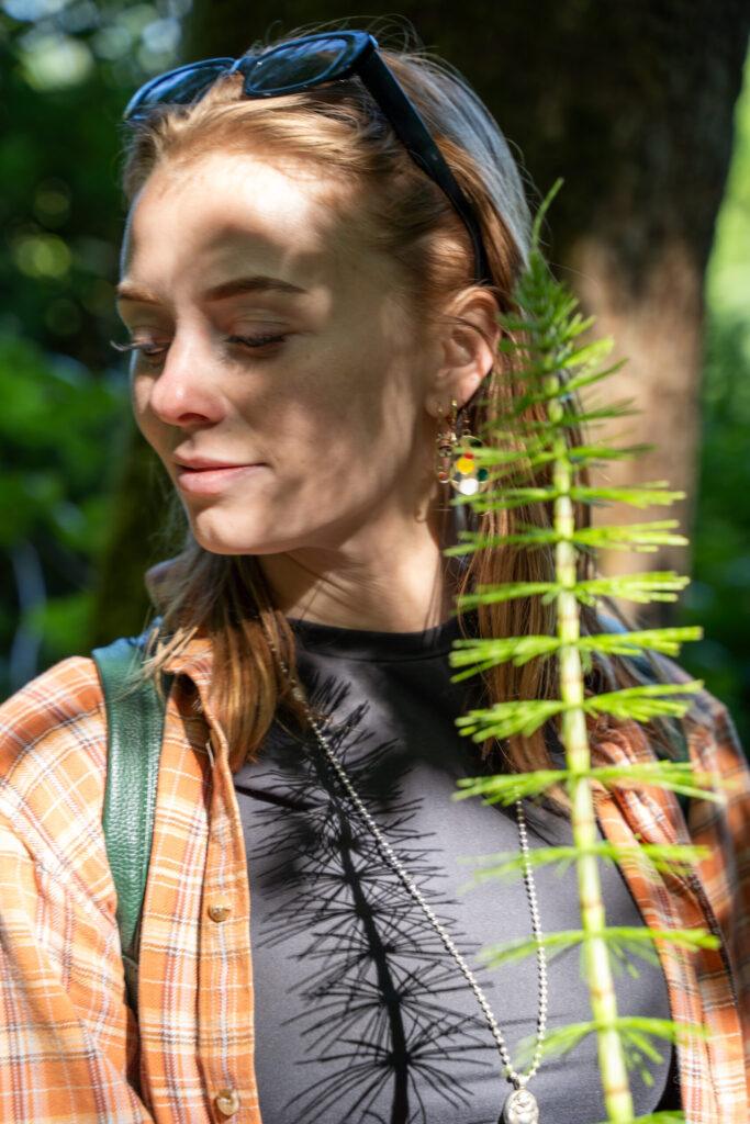 Portret van een vrouw in het Kralingse Bos in Rotterdam, met een plant op de voorgrond voor extra diepte.