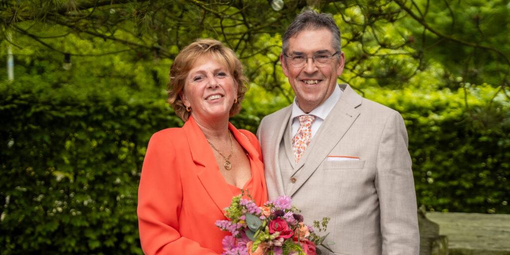 Bruidspaar poseert samen met boeket in een groene omgeving in Rotterdam.