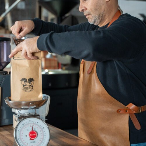 Koffiebrander weegt vers gebrande koffiebonen in een zak bij Lorando & Morini.