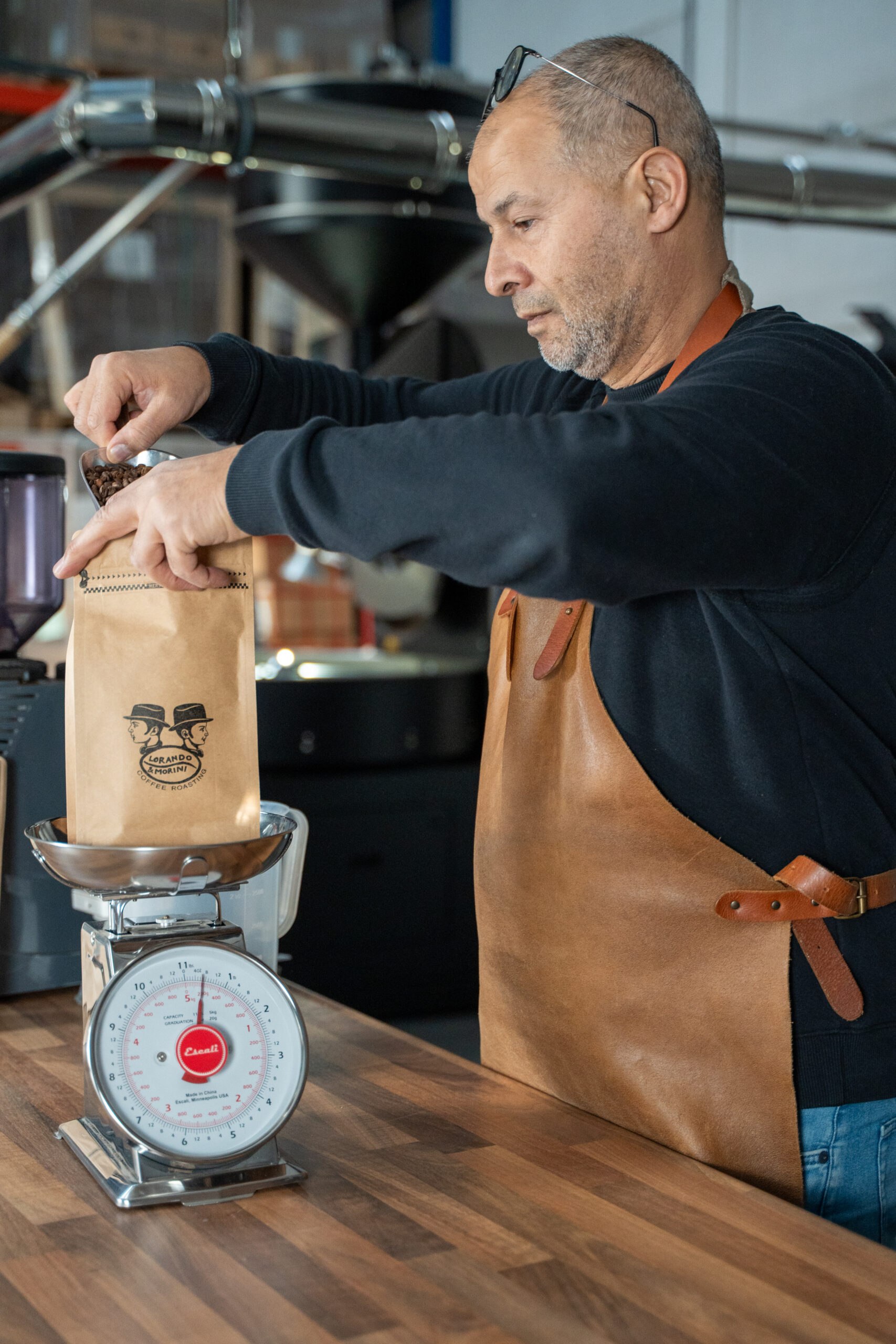 Koffiebrander weegt vers gebrande koffiebonen in een zak bij Lorando & Morini.