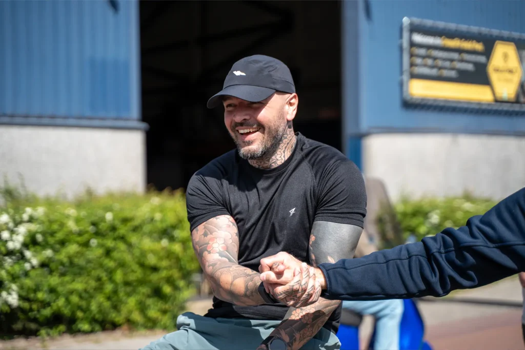 Getatoeëerde man lacht tijdens evenement bij de Gold Pact stage.
