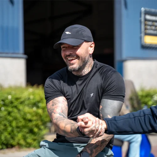 Getatoeëerde man lacht tijdens evenement bij de Gold Pact stage.