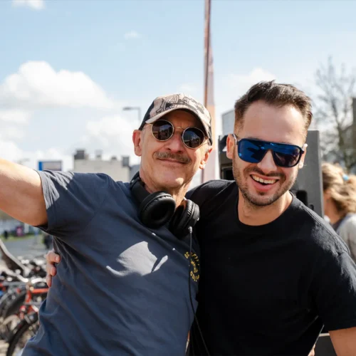 Twee mannen poseren lachend bij de Gold Pact aanmoedigingsstage tijdens de marathon.