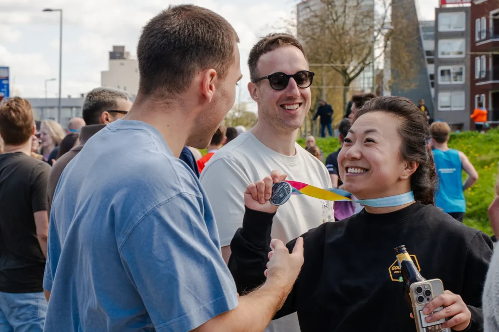 Vrouw laat haar medaille zien na de marathon bij de Gold Pact stage.