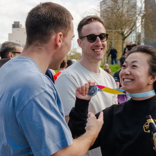Vrouw laat haar medaille zien na de marathon bij de Gold Pact stage.