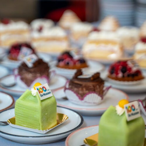 Verschillende gebakjes met jubileumlogo van De Mussen tijdens het 100-jarig bestaan.