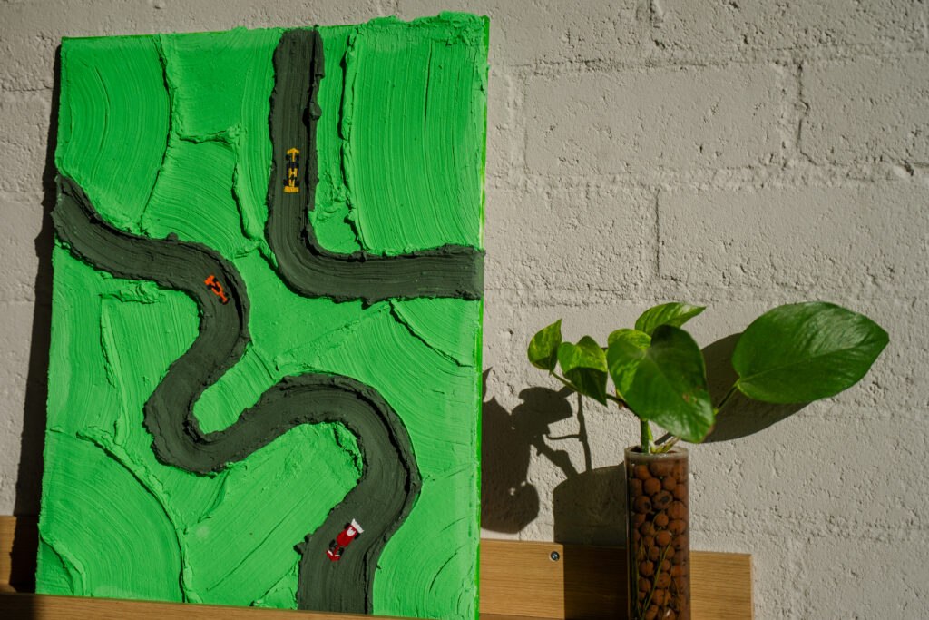 Abstract kunstwerk met een racebaan en miniatuur raceauto's op een groene achtergrond.