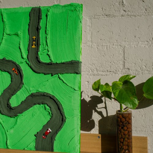 Abstract kunstwerk met een racebaan en miniatuur raceauto's op een groene achtergrond.