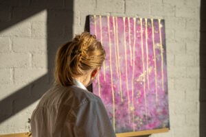 Bezoeker bekijkt een roze abstract schilderij met gouden details in het atelier van Studio Isobel.