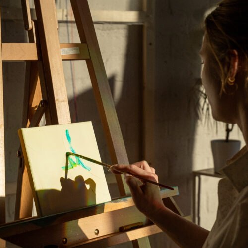 Kunstenaar schildert een nieuw kunstwerk op een ezel in het atelier van Studio Isobel.