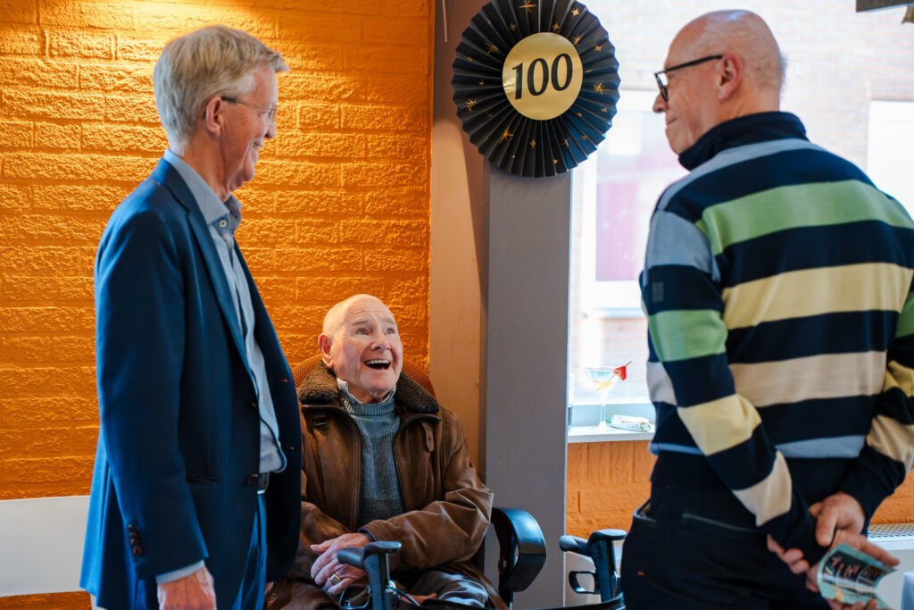 Bezoekers met een feestelijk boeket tijdens de viering van 100 jaar De Mussen.
