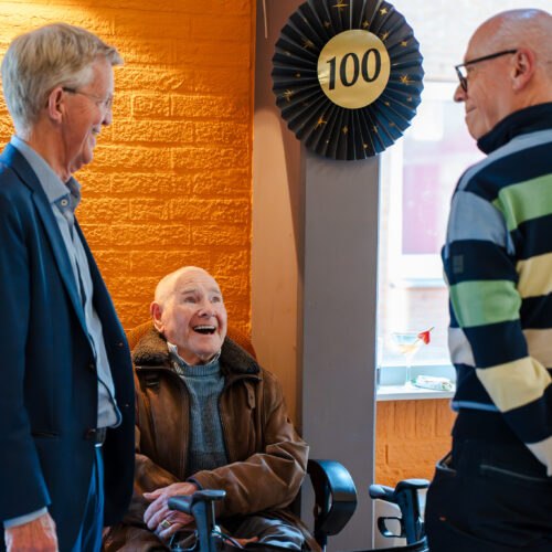 Bezoekers met een feestelijk boeket tijdens de viering van 100 jaar De Mussen.