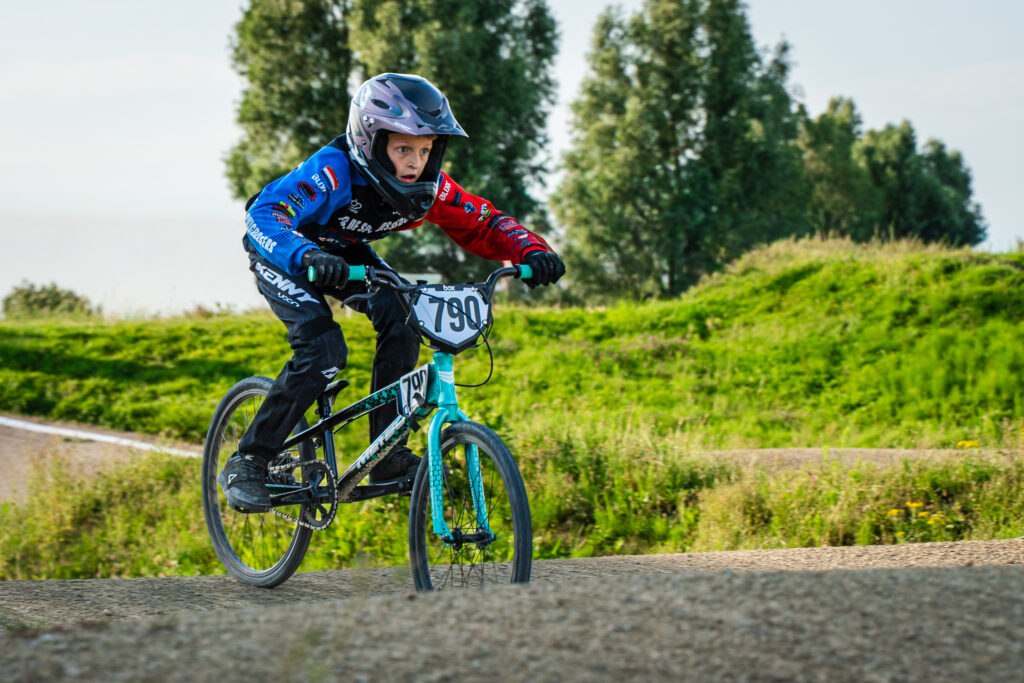 Jonge BMX-rijder vliegt over een heuvel tijdens de wedstrijd bij Fietscross Club Barendrecht.