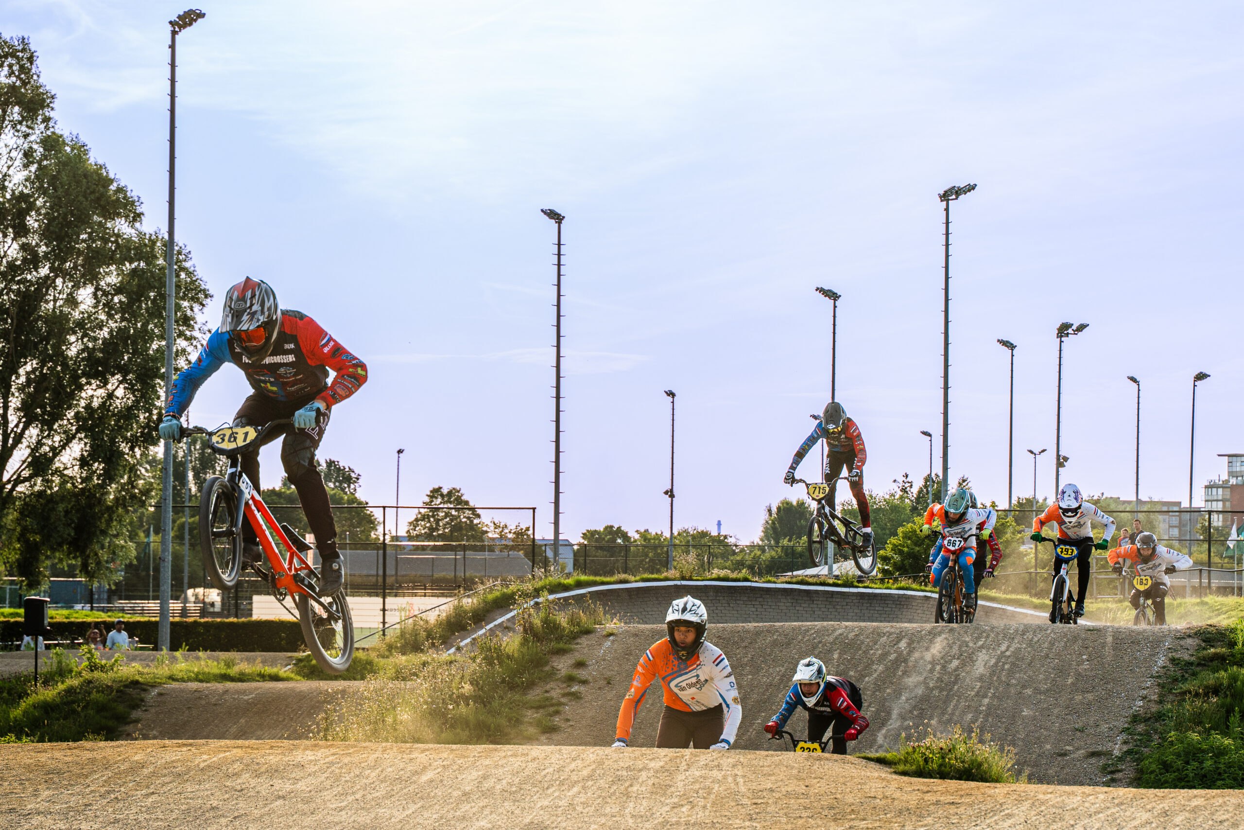 Breed overzicht van meerdere BMX-rijders verspreid over de baan.