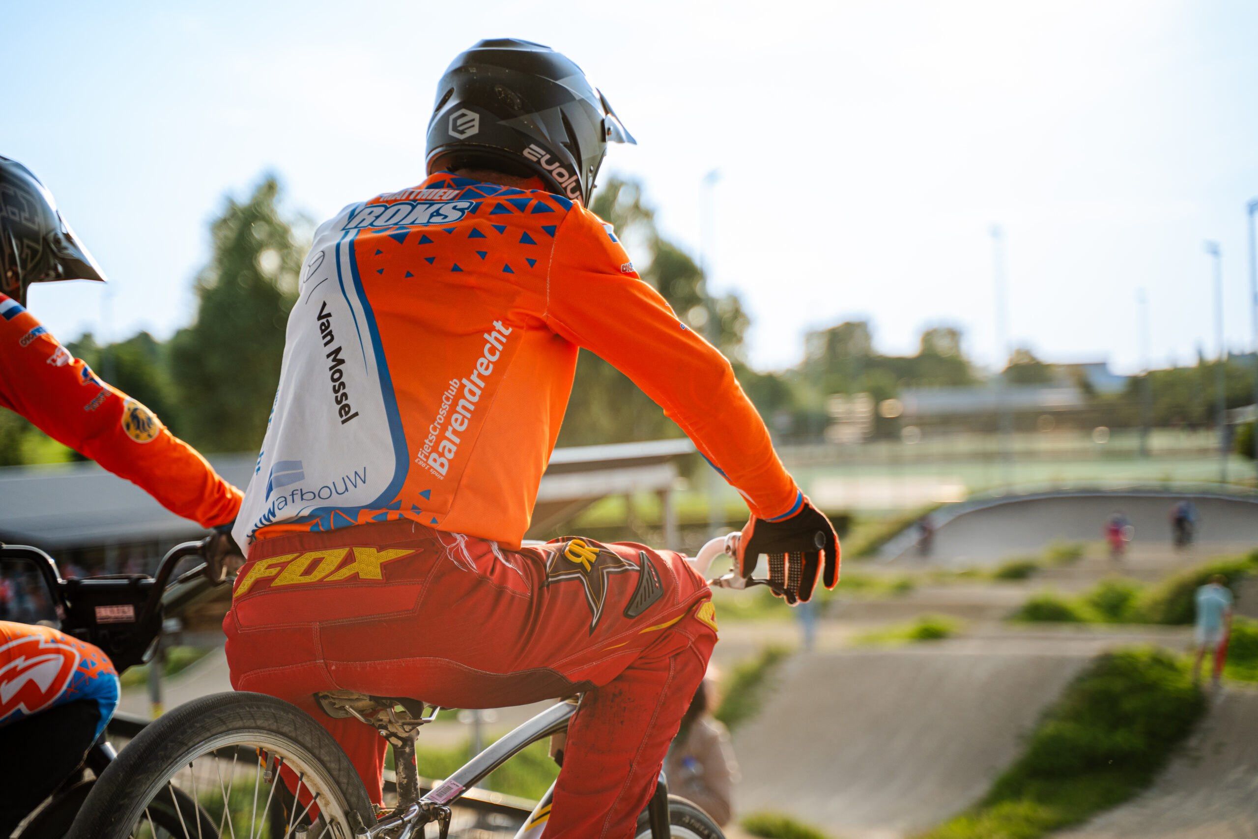 BMX-rijder wacht bovenaan het starthek en kijkt uit over de baan.