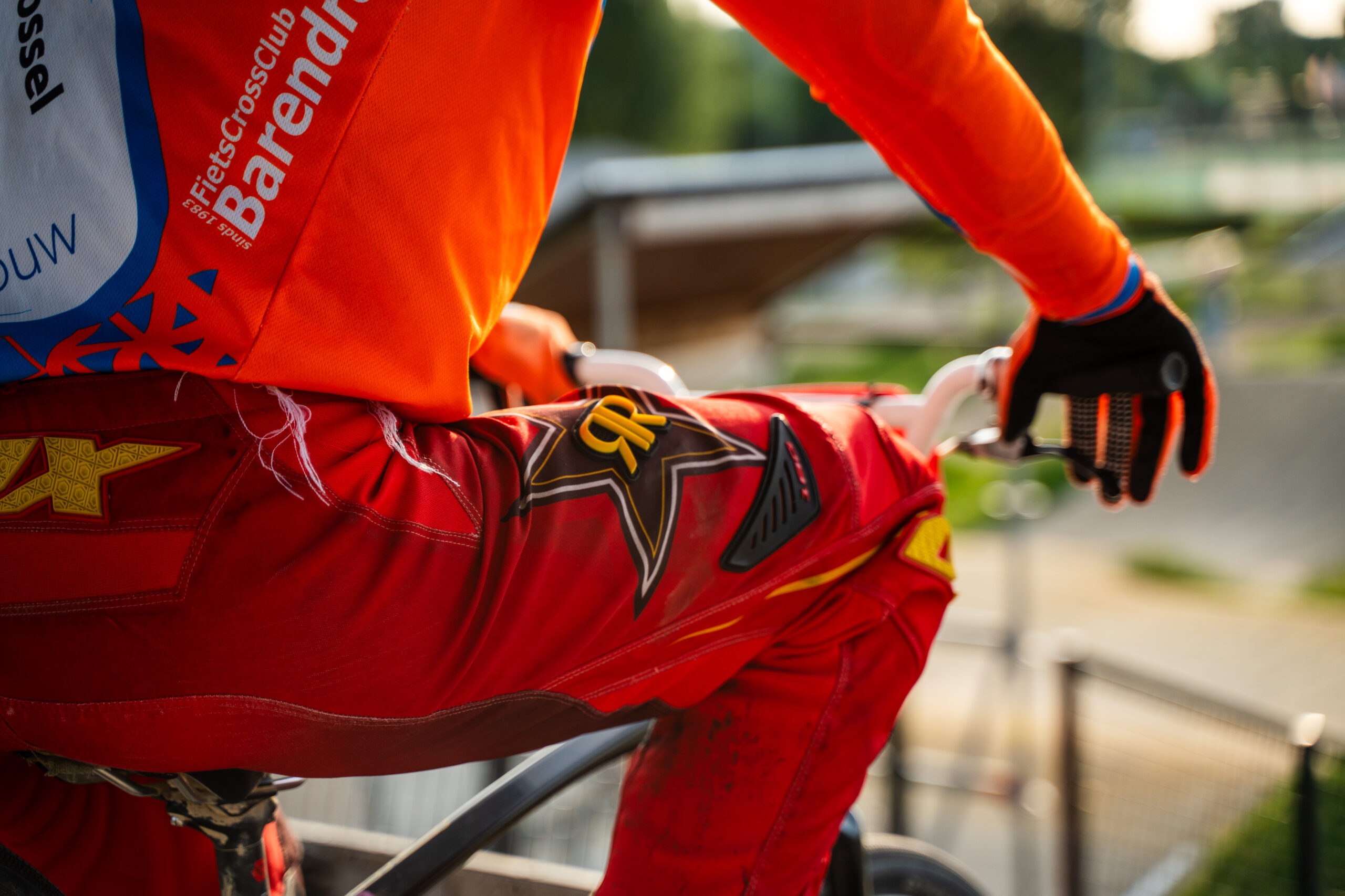 Detailfoto van BMX-uitrusting en wedstrijdkleding van een rijder.