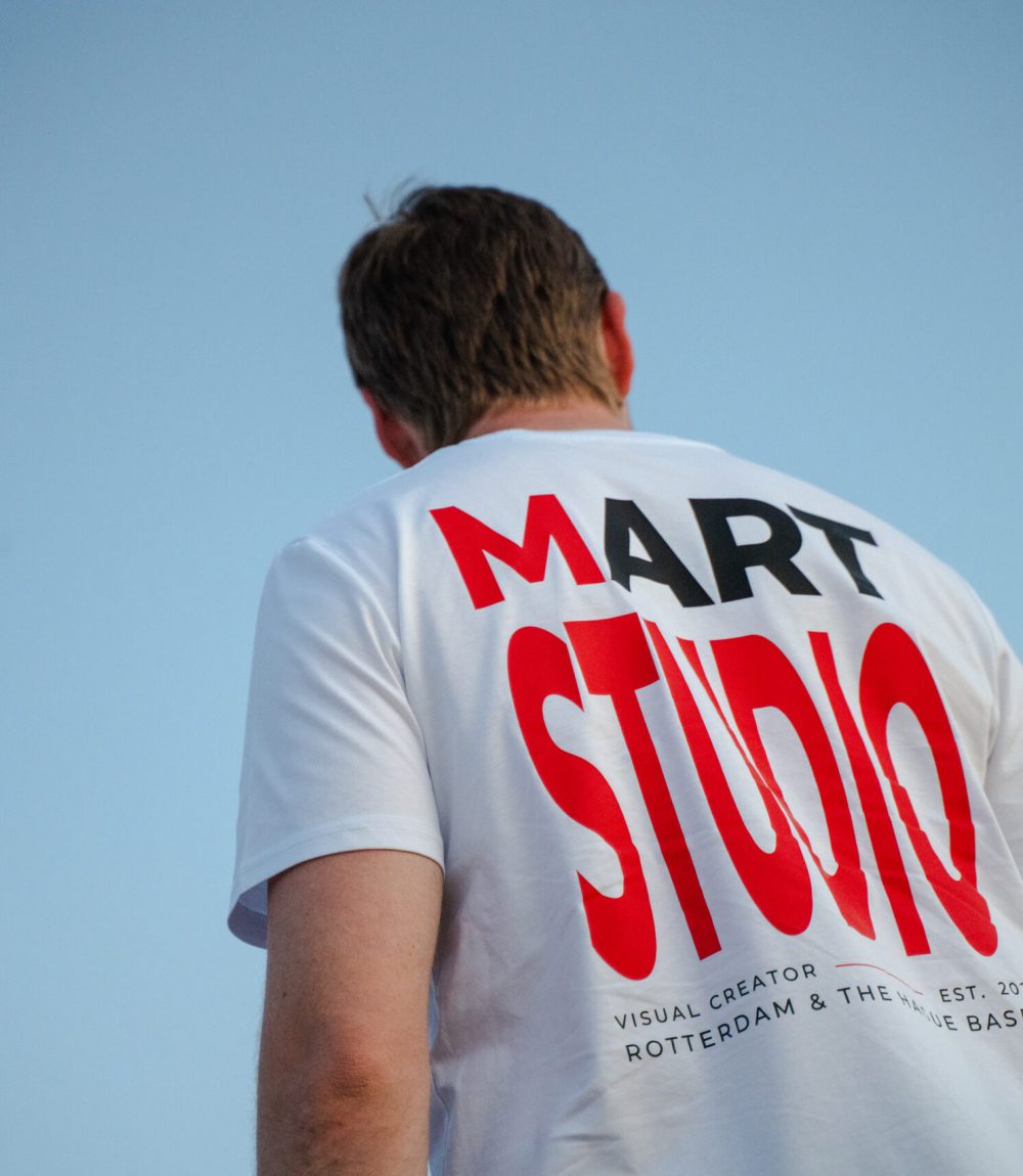 Achterkant wit T-shirt met groot Mart Studio logo in rood en zwart