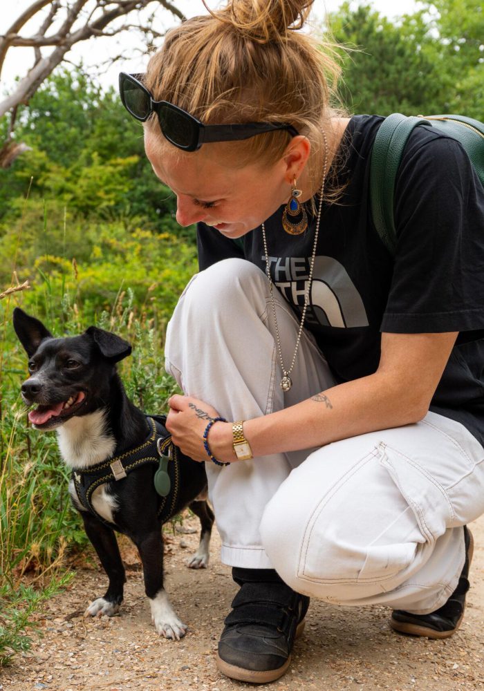 Vrouw zit gehurkt bij haar hond op een pad nabij Scheveningen in Den Haag, vastgelegd in spontane lifestyle fotografie.