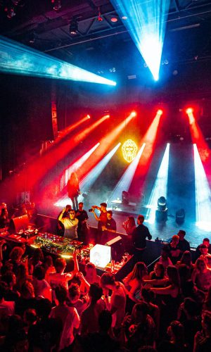 Grote dansvloer vol publiek met sterke lichtbundels tijdens een clubnacht in PAARD.
